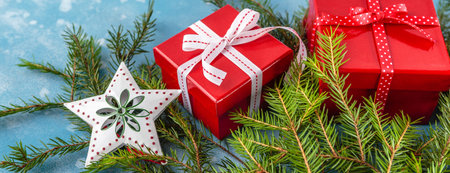Christmas red box gifts, decorations and spruce branches on blue background