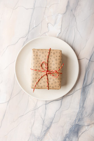 Two gift boxes packed in craft paper on a background of pink marble