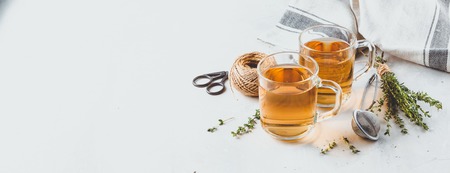 Transparent glasses cup of herbal tea with thyme and sprigs of thyme tied in a bunch on a white background. Web banner with copy spaceの写真素材