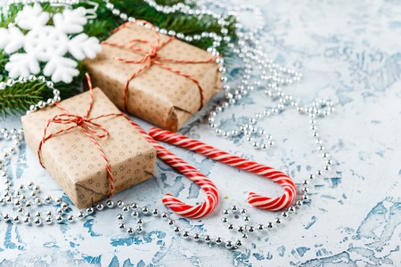 Christmas gift boxes, fir branch with cones, candy canes on a light backgroundの写真素材