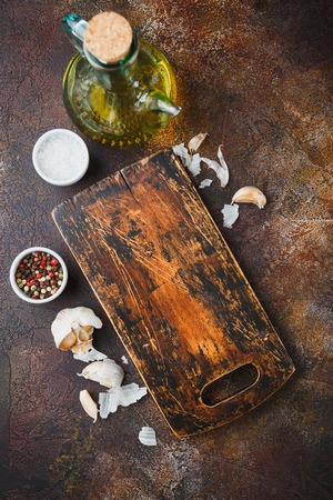 Wooden cutting board, olive oil, salt, pepper, garlic and thyme sprigs on a dark background. Top view Copy spaceの写真素材