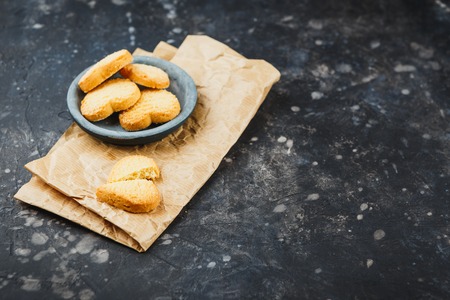 Shortbread cookies in the form of hearts in a small plate on a dark background. Space for text.の写真素材