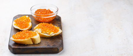 Sandwiches with red caviar and butter in plate on wooden table. Top viewの写真素材
