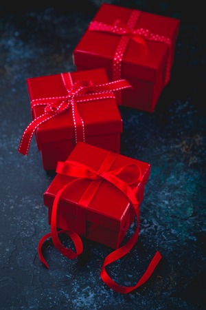 Gift red boxes with red bow ribbons and hearts on dark background for Valentines day.の写真素材