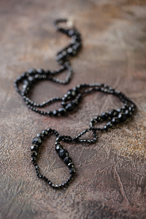 Elegant Black necklace closeup on dark brown backgroundの写真素材