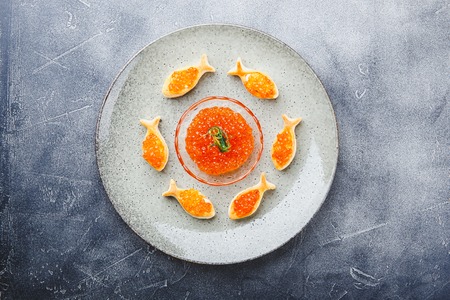 Delicious puff pastry tartlets in the shape of fish with red caviar on a festive table.の写真素材