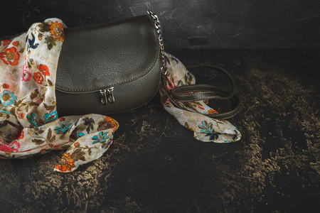 Women's autumn clothing and accessories - scarf and bag, on dark wood surfaces, vintage styleの写真素材