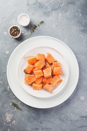 Diced pieces of salmon for marinating on white plate. Top view.の写真素材