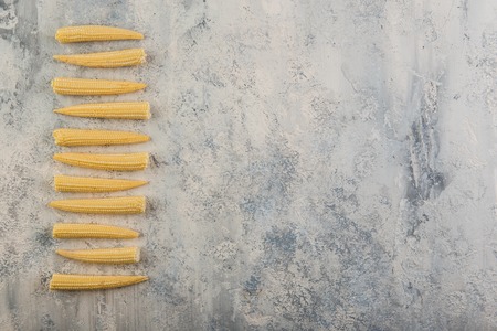 Fresh young baby corn on grey concrete background. Space for text.の写真素材