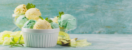 Mint and lemon ice cream with mint leaves in ceramic bowl on green wooden background. Space for...