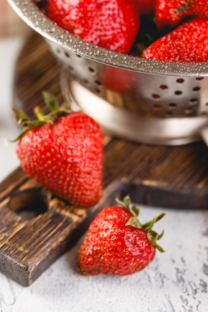 Fresh berries strawberries in a while colander on grey backgroundの写真素材
