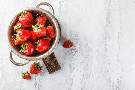 Fresh berries strawberries in a while colander on grey background with copy space. Top view.の写真素材