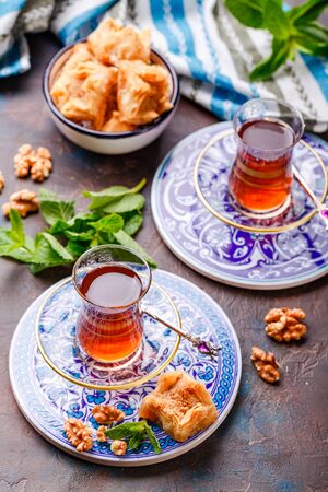 Middle Eastern or Arabic tea with mint in a traditional glass cup and Turkish sweetness Baklava. Ramadan kareem. Eid mubarak. Islamic holidays decoration.の写真素材