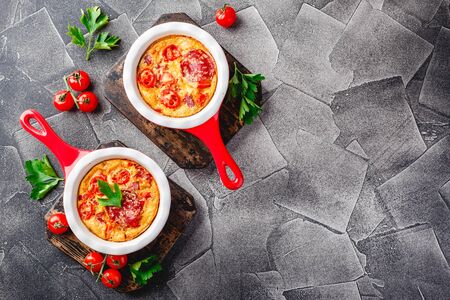 Frittata with sweet peppers, tomatoes and salami in ceramic skillet. Kind of Italian omelette with vegetables. View from aboveの写真素材