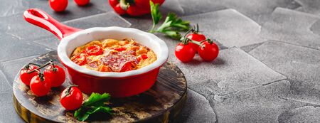 Frittata with sweet peppers, tomatoes and salami in ceramic skillet. Kind of Italian omelette with vegetables.の写真素材