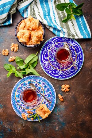 Middle Eastern or Arabic tea with mint in a traditional glass cup and Turkish sweetness Baklava. Ramadan kareem. Eid mubarak. Islamic holidays decoration.の写真素材