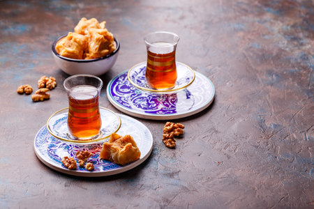 Traditional Turkish black tea in glass at decorative plates on concrete background
