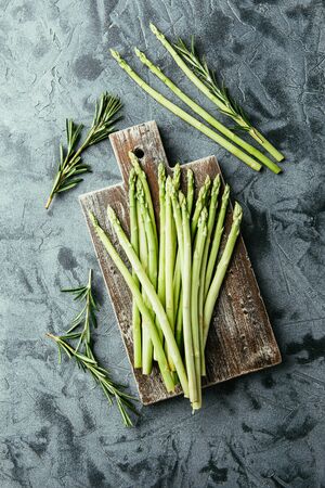 Fresh raw green asparagus on wooden cutting board on gray background. Top view.の写真素材