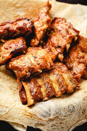 Grilled pork ribs on thin pita in plate on brown backgroundの写真素材