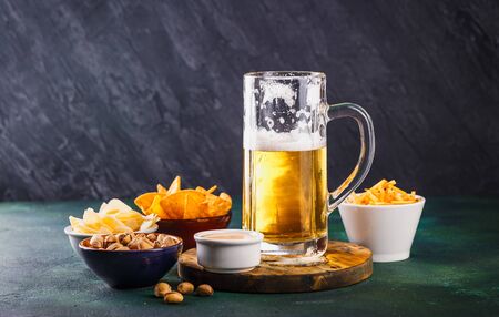 Glass mug with beer with foam and water drops on a dark green backgroundの写真素材