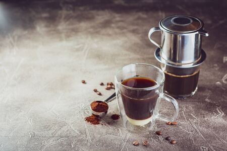 Vietnamese coffee with condensed milk in glass cups and traditional metal coffee maker phin. Traditional method of making of vietnamese coffee. Space for text.の写真素材