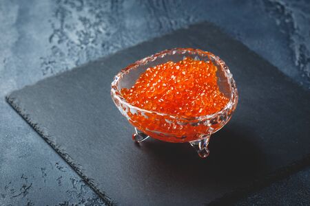 Salmon red caviar in crystal plate with spoon on black background. Exquisite delicacyの写真素材