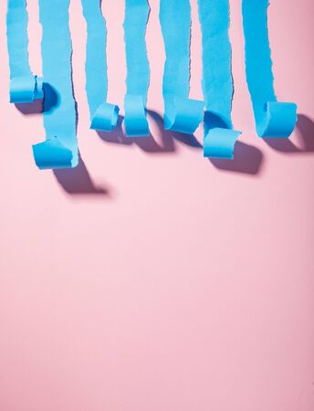Strips of torn blue paper on a pink backgroundの写真素材