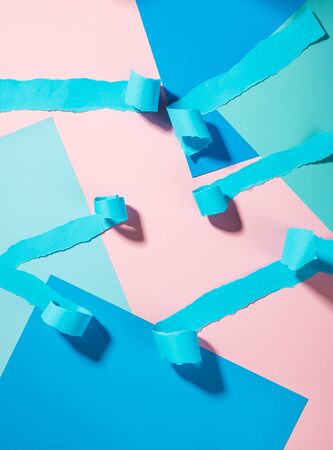 Strips of torn blue paper on a pink backgroundの写真素材