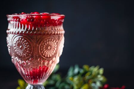 Cranberry cocktail with ice in beautiful vintage glass on dark background. Copy spaceの写真素材