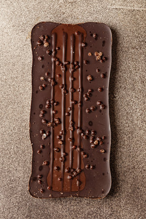 Top view of Dark chocolate bar with milk and crispy chocolate balls on a brown background close-up