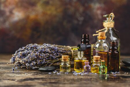 Glass bottles aroma oil, zen stones and dry lavender flowers on wooden table. Spa Treatmentの写真素材