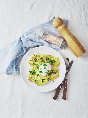 Vegetable zucchini pancakes with poached egg on white plate. Top viewの写真素材