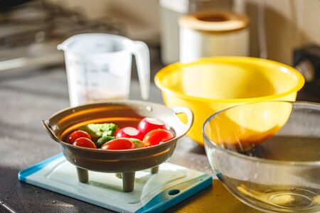 Washed vegetables in a colander on the kitchen table for making salad - radishes, cucumbers, tomatoes, herbsの写真素材
