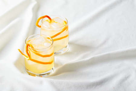 Summer refreshing cocktails, lemonade or mojito with orange zest and ice in a glass on white background. Place for text.の写真素材
