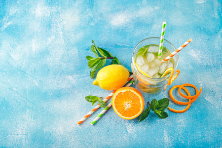 Summer refreshing cocktails, lemonade or mojito with lemon, orange and mint with ice in a glass cup...
