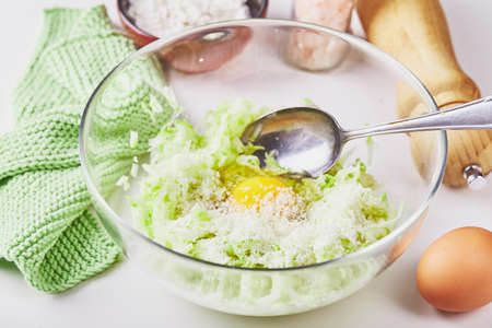 Ingredients for cooking zucchini pancakes or fritters - grated zucchini, egg, flourの写真素材