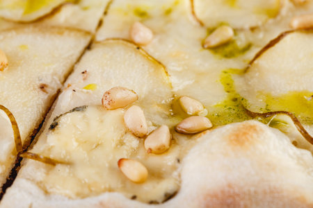 Pizza with pears and blue cheese on a wooden board on a dark background. Close-up