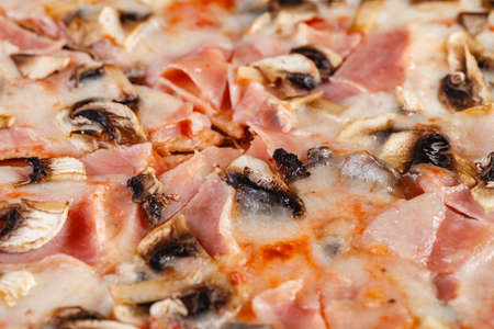 Pizza with ham and mushrooms on a wooden board on a dark background. Close-upの写真素材