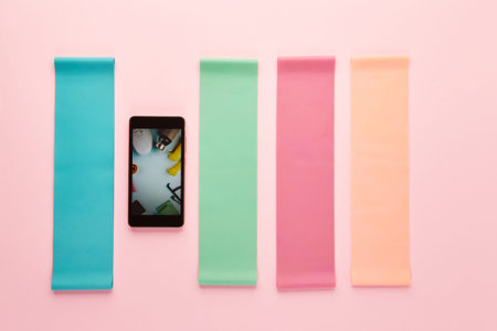 Resistance Bands for Legs and Butt and smartphone on pink background. Creative flat lay of sport and...