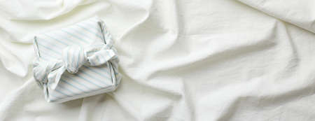 Eco-friendly gift wrap in traditional japanese furoshiki style on fabric background, eco-friendly gift wrap and Zero Wast concept. Long wide bannerの写真素材