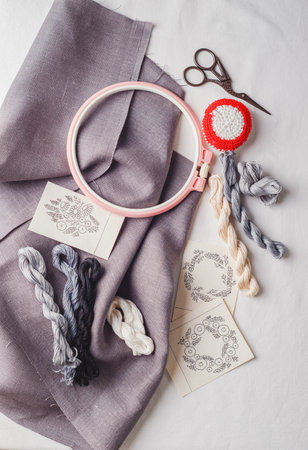 Set for embroidery. Linen fabric, patterns for embroidery, hoop, thread of white, black and gray colors and needles. Copy space, top viewの写真素材