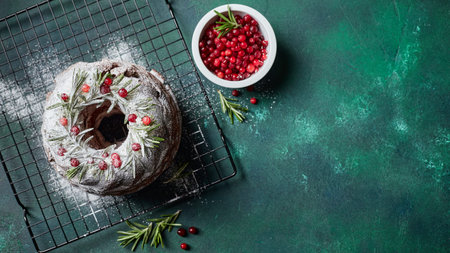 Christmas homebaked dark chocolate bundt cake decorated with powdered sugar and fresh cranberries on...