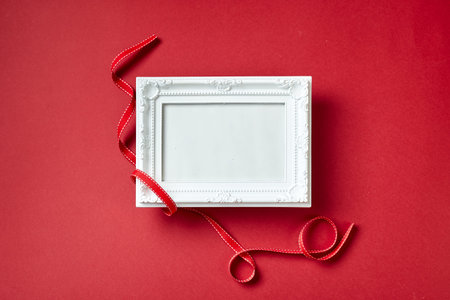 Photo frame and Valentines day hearts and decorations on red background. Top view with copy space....