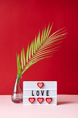 Love lightbox message with red hearts and palm leaf on pink and red backgroundの写真素材