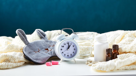 Sleeping mask, alarm clock, earplugs, essential oils and pills. Healthy night sleep creative concept. Good night, sleep hygiene, insomniaの写真素材