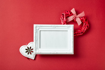 Photo frame and Valentines day hearts and decorations on red background. Top view with copy space. Valentines day concept.の写真素材