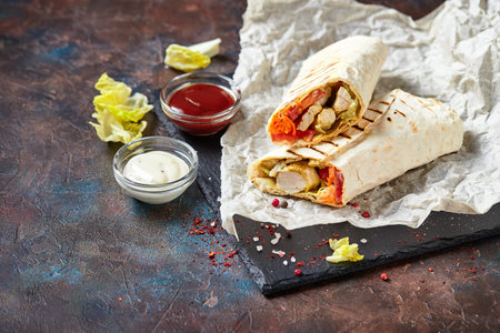 Eastern traditional shawarma with chicken and vegetables, Doner Kebab with sauces on slate. Fast...