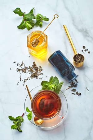 Black tea in glass transparent mug with mint leaves and honey. Calming and revitalizing tea, anti-stress and relaxationの写真素材