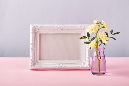 Flower of yellow matthiola in little glass vase with white photo frame. Design concept of holiday...