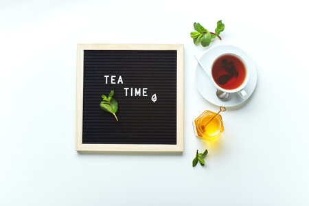 Tea time. Black letter board with text on marble table with glass cup of tea with mint leavesの写真素材
